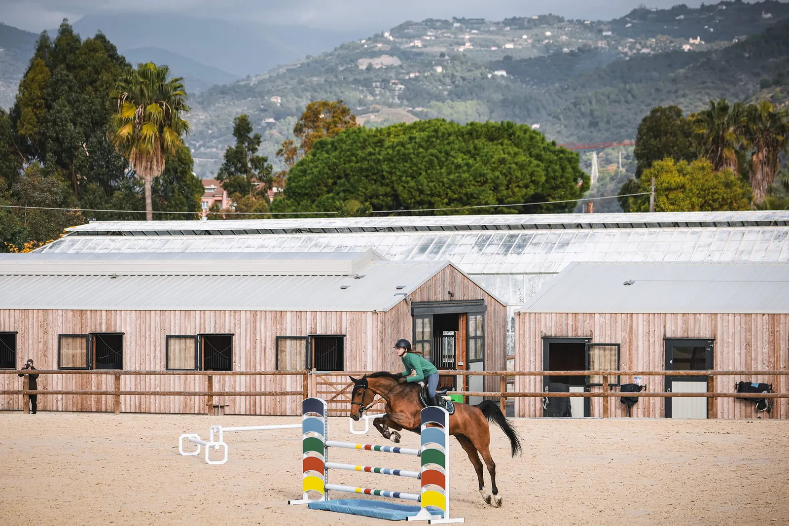 Centre équestre Liguria Jumping, écuries en bois et carrière de saut d’obstacle face aux collines de la riviera ligure